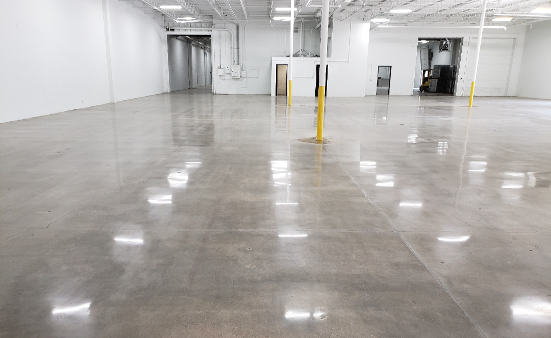 A large empty warehouse with a shiny concrete floor and white walls.