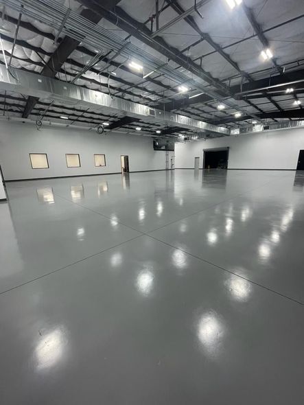 A large empty warehouse with a gray floor and white walls.