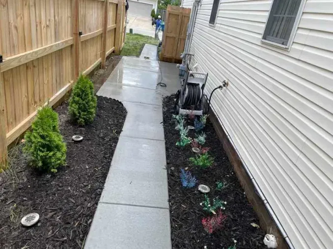 A sidewalk leading to a house with a wooden fence.