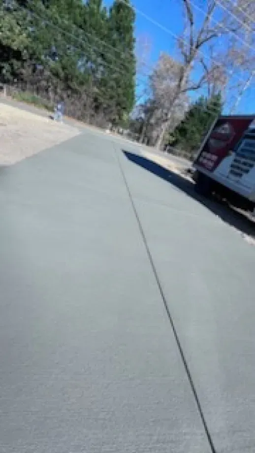 A concrete sidewalk with a van parked on the side of it.
