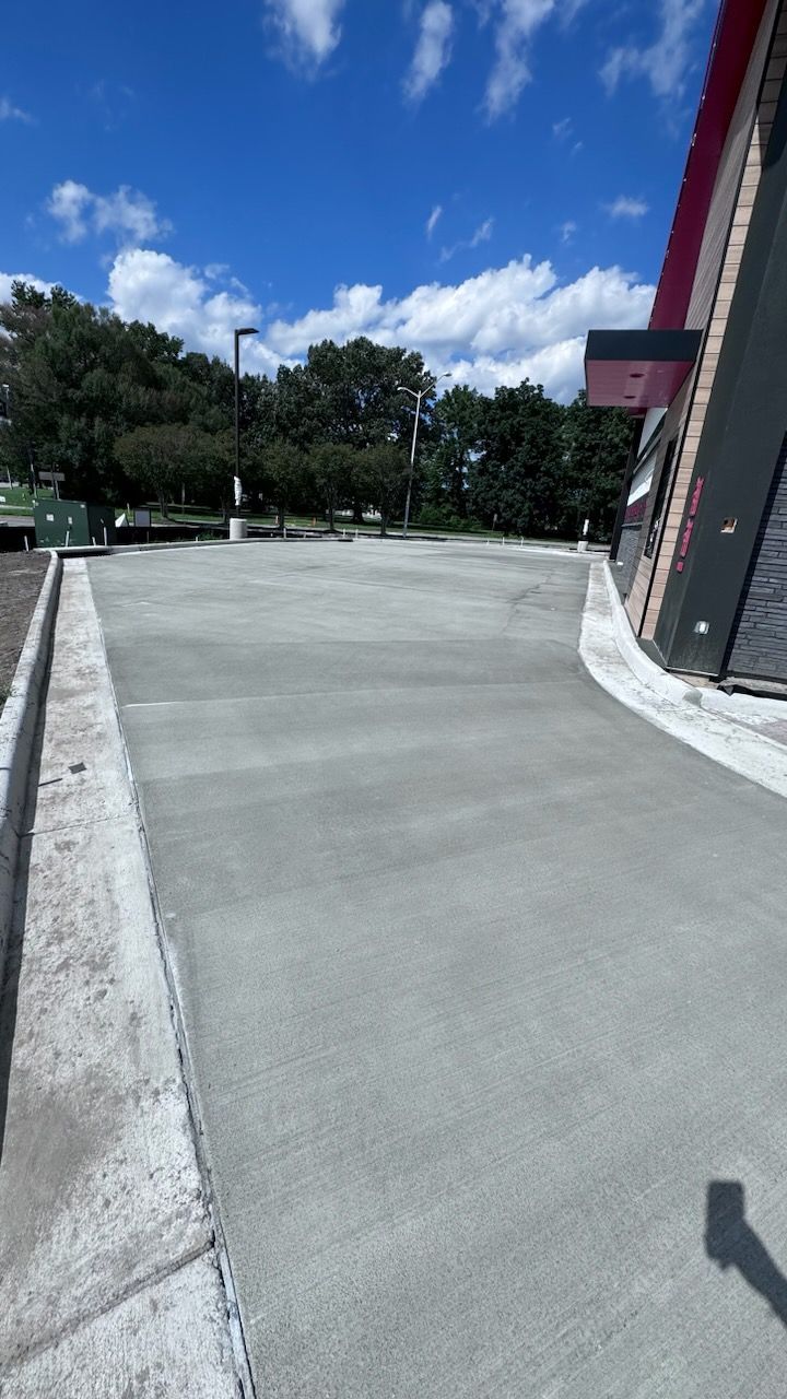 A concrete driveway leading to a building on a sunny day.