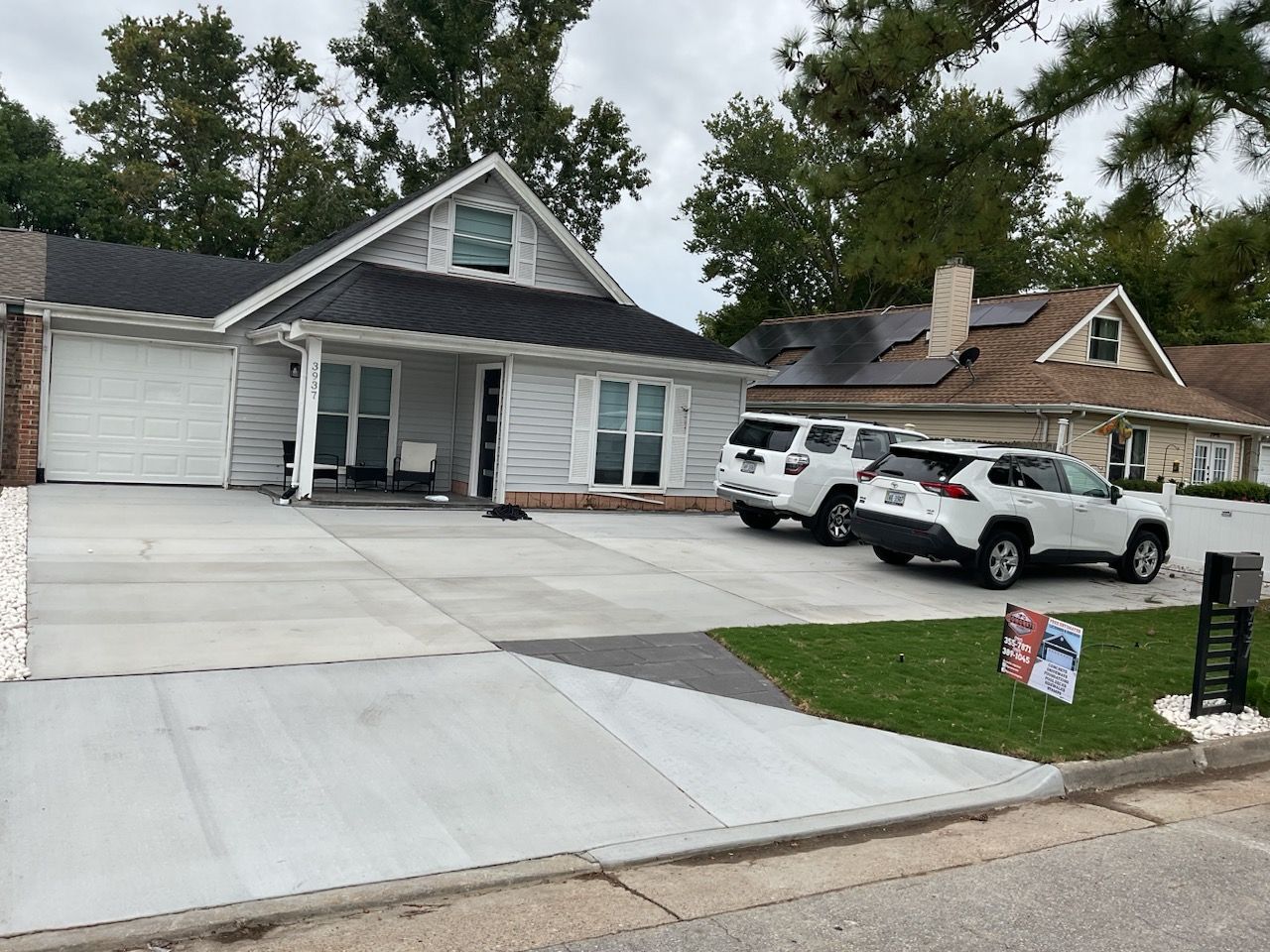 A couple of cars are parked in front of a house.
