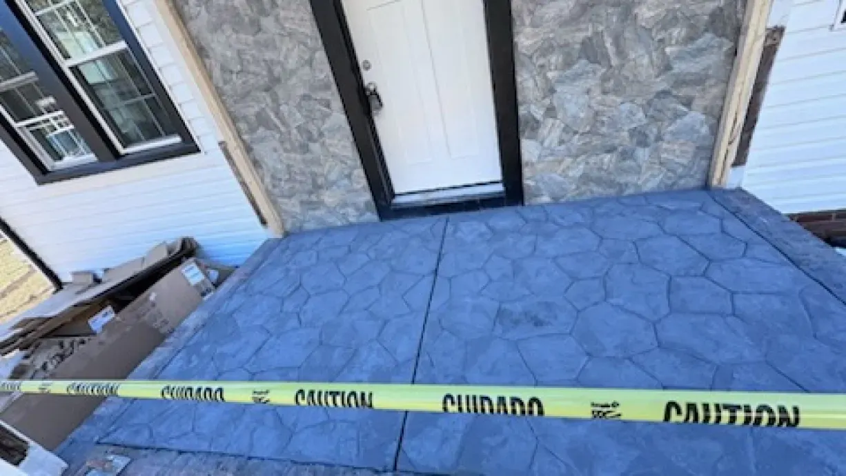 A yellow caution tape is laying on the ground in front of a house.