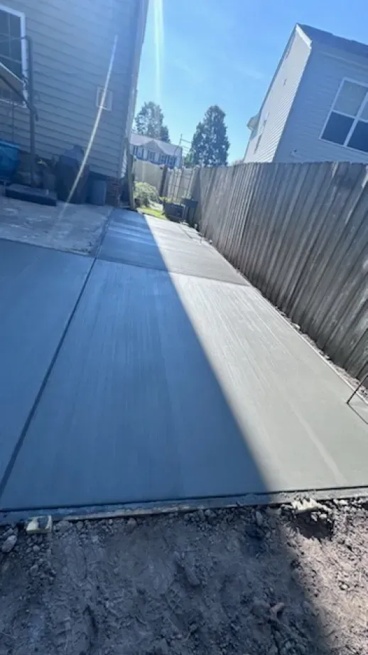 A concrete driveway is being built in the backyard of a house.