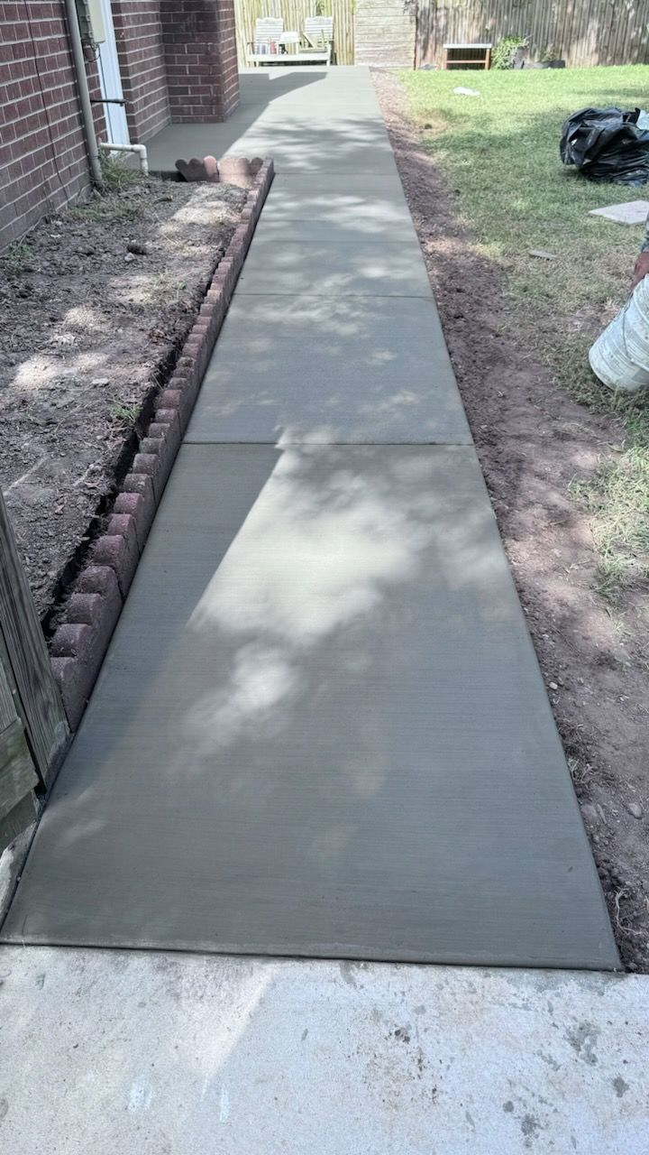 A concrete walkway is being built next to a brick building.