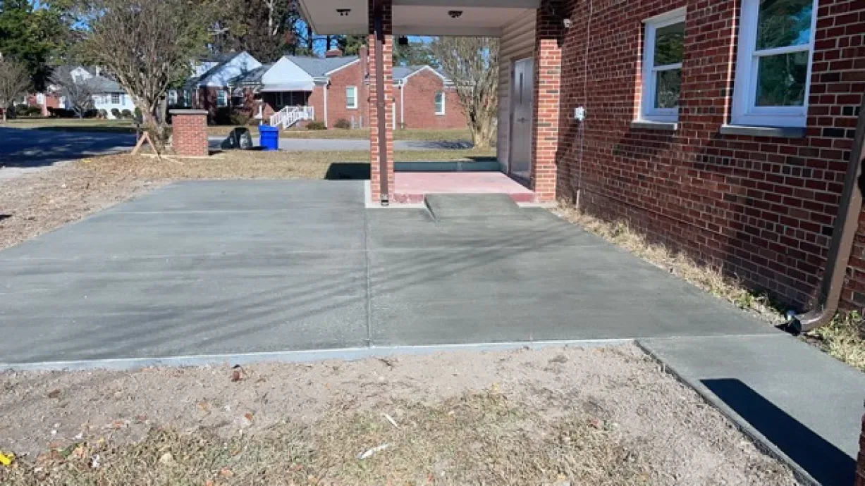 A brick building with a concrete driveway in front of it.