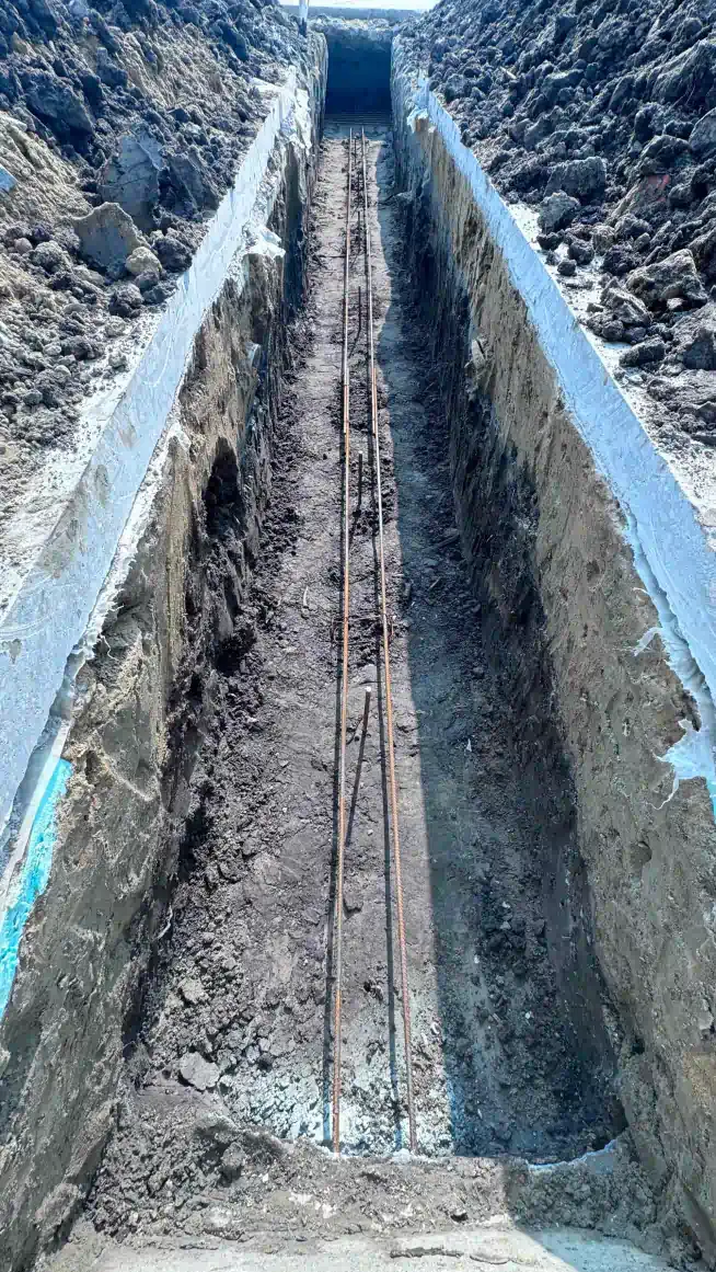 A long trench filled with dirt and rocks leading to a tunnel.