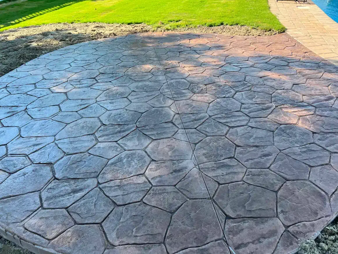 A concrete patio with a hexagonal pattern and a pool in the background.