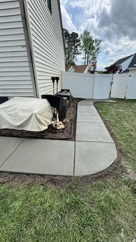 A concrete walkway in the backyard of a house.