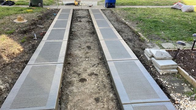 A concrete walkway is being built in a yard.