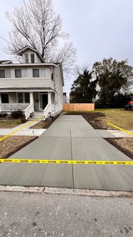 A concrete walkway is being built in front of a house.