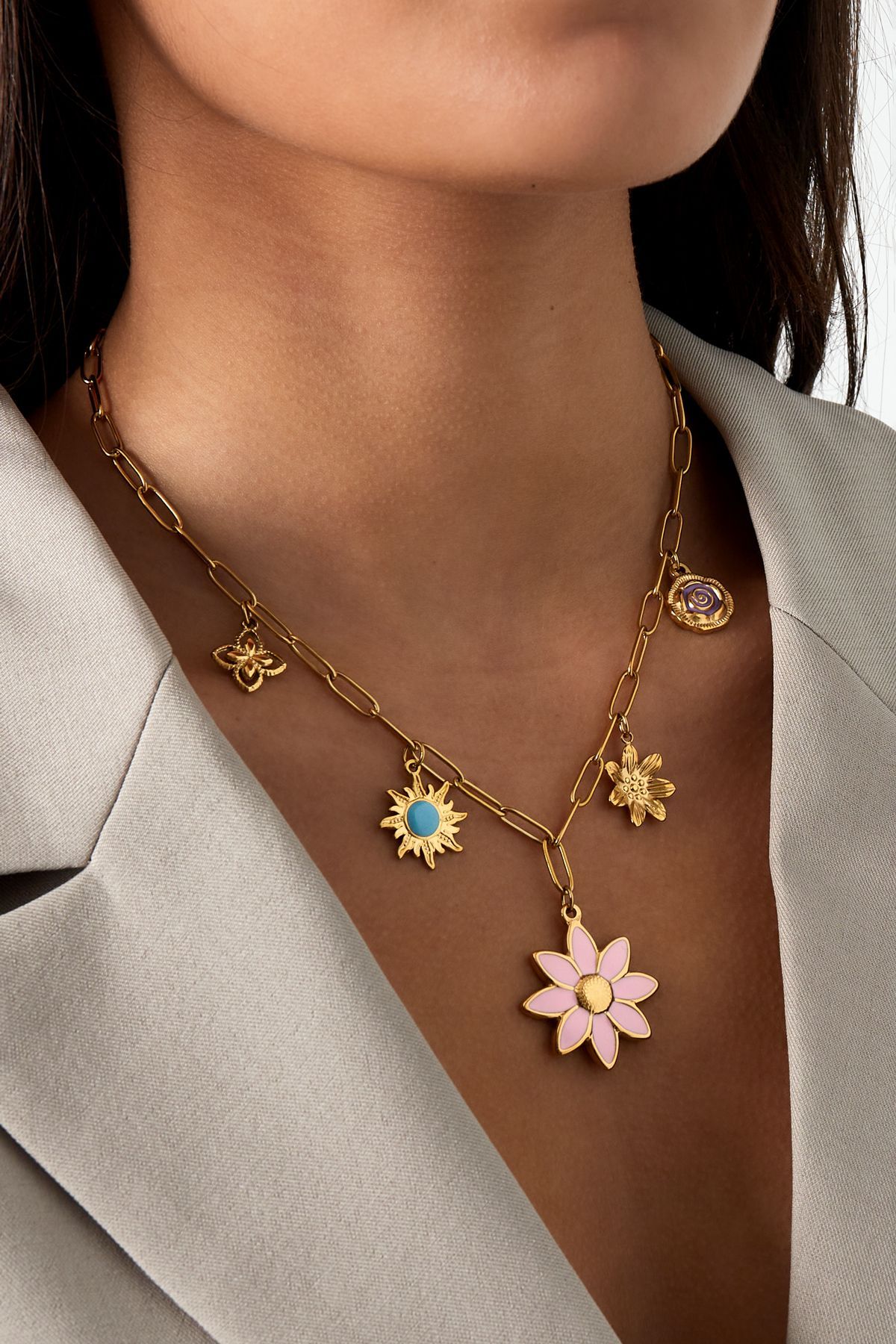 Gouden ketting met vijf delicate bloem- en vlinderbedeltjes in pastelblauw, roze en wit emaille.