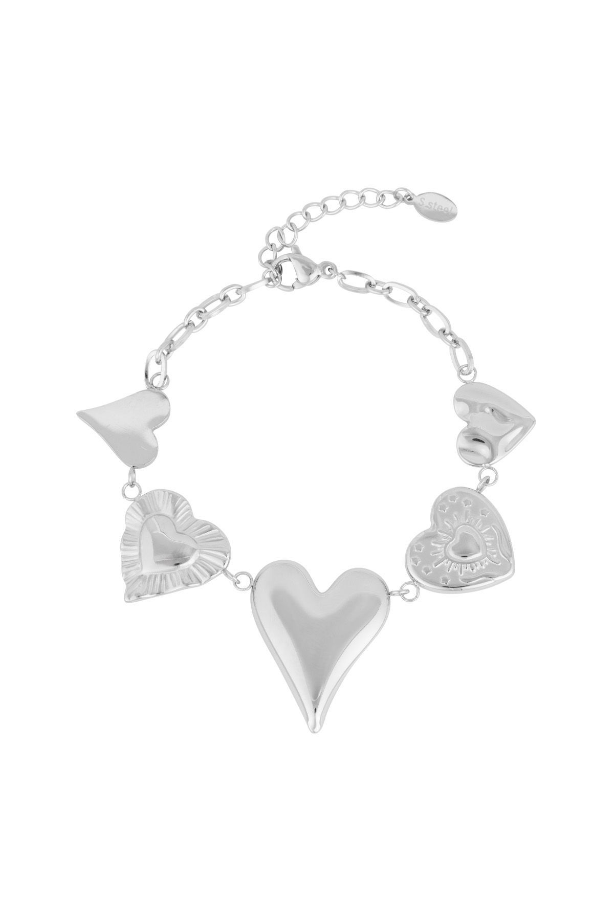 Zilveren schakelarmband met vijf verschillende hartvormige bedeltjes die aan schakels hangen, afgebeeld op een witte achtergrond.