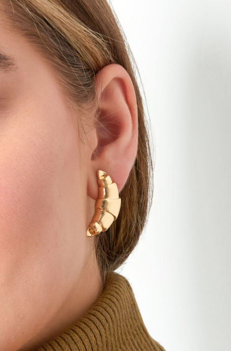 Een paar gouden, halvemaanvormige oorknopjes in de vorm van een croissant, geplaatst tegen een effen witte achtergrond.