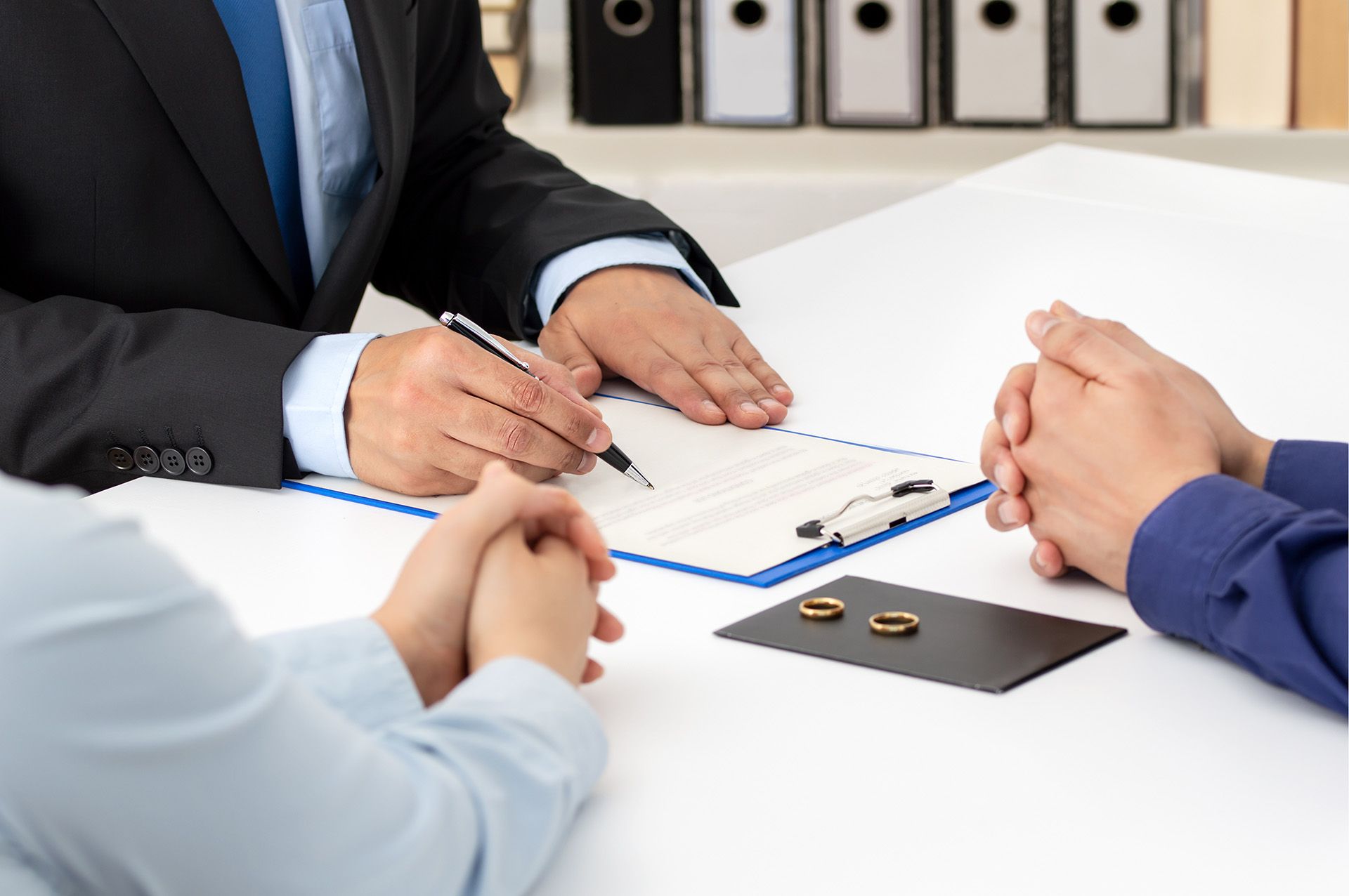 A lawyer going over a legal document with a couple and their rings are on the table. 