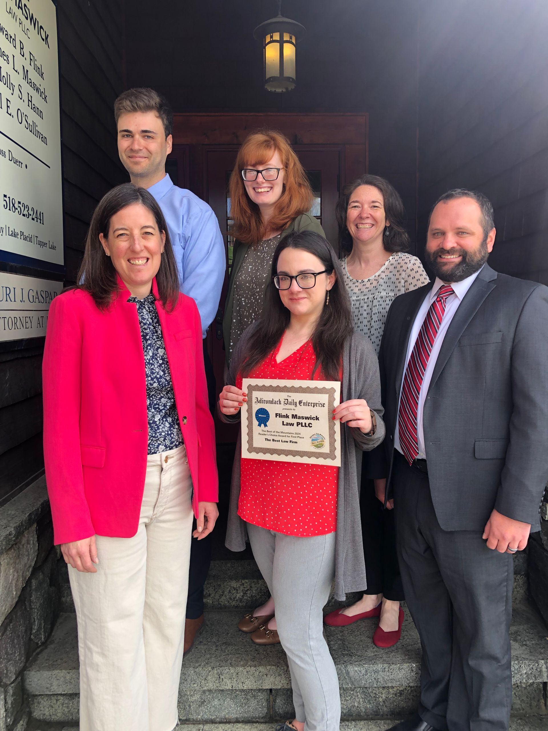 The Flink Maswick Law team is in front of their office holding the best of the mountains award.