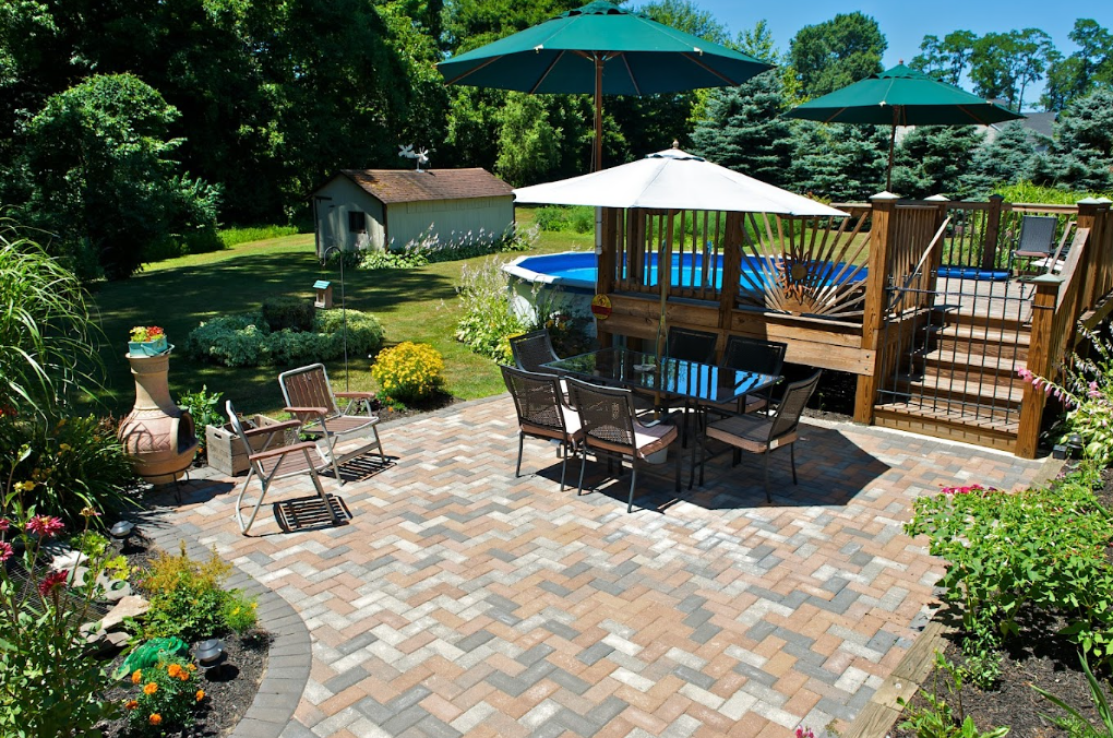 Backyard patio with table, chairs, umbrella, small pool, and lush garden landscaping
