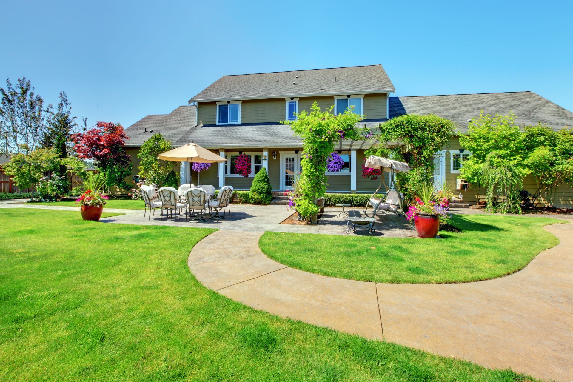 a large house with a lush green lawn and a walkway leading to it .