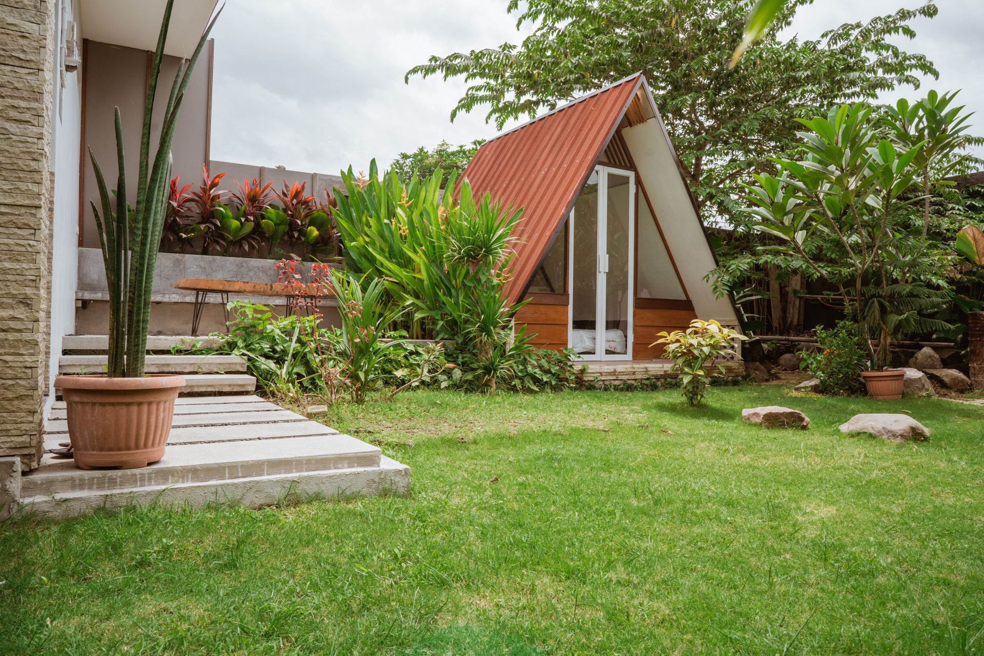 a small house with a red roof is sitting in the middle of a lush green yard .