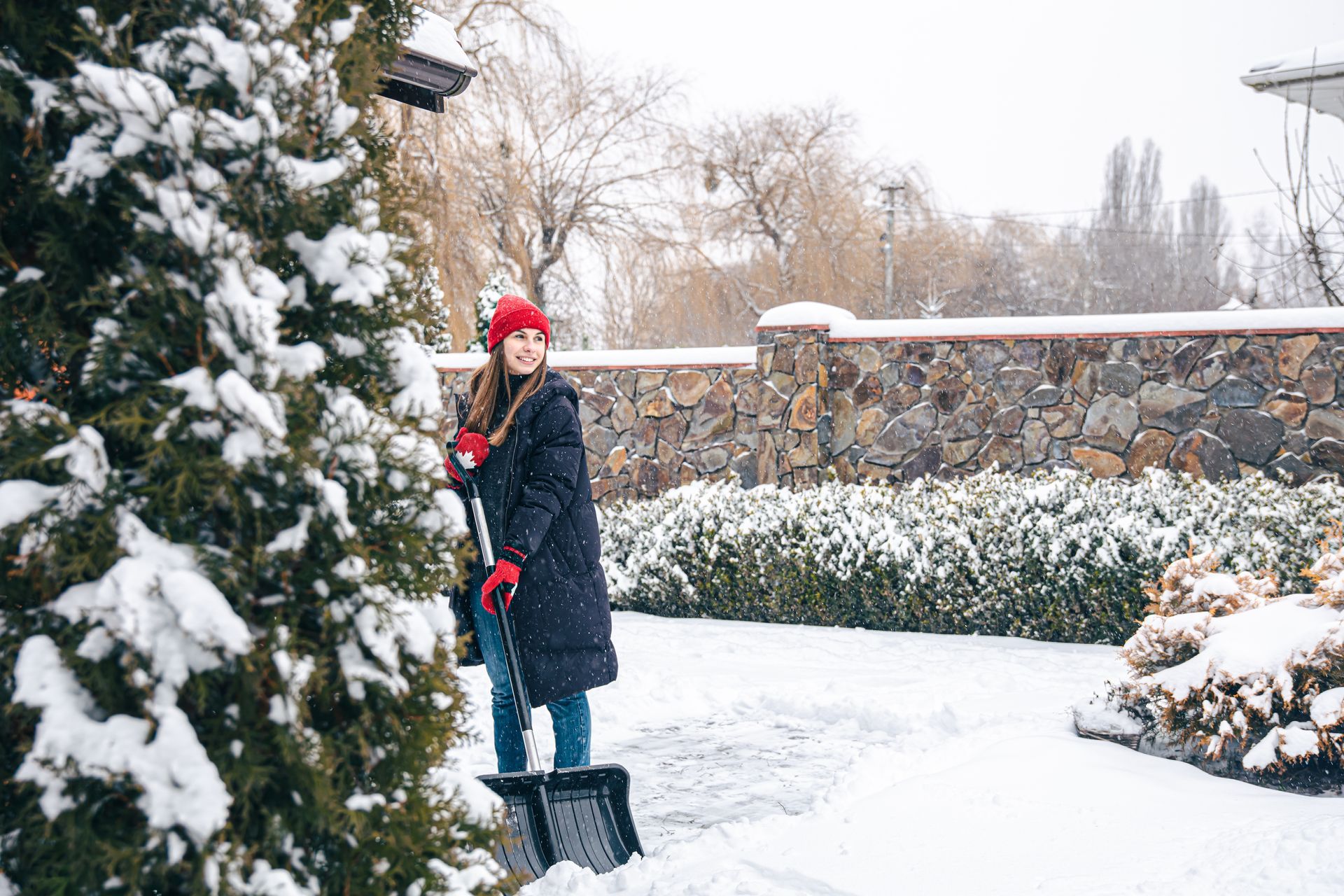 a woman is shoveling snow from a driveway .