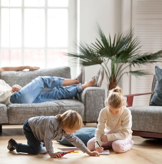 A boy and a girl are sitting on the floor in a living room.