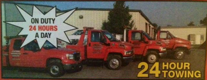 Four red tow trucks parked in front of a building. Text reads 