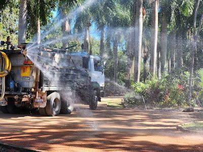 Truck Spraying Water in a Dirt Road Surrounded by Trees — AGM HIRE NQ in Kirwan, QLD