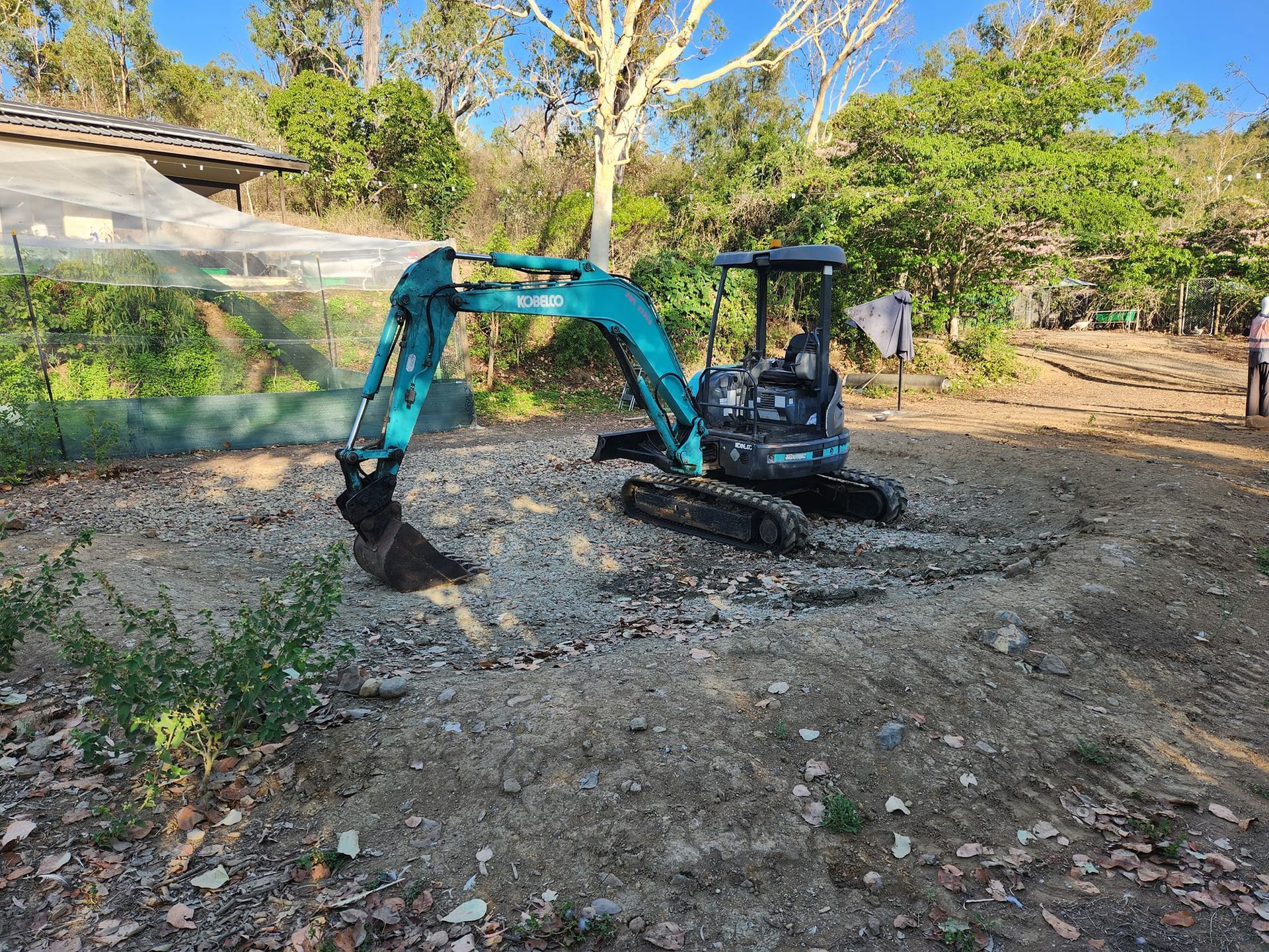 A Teal Mini-excavator Sits on a Gravelly Surface — AGM HIRE NQ in Condon, QLD