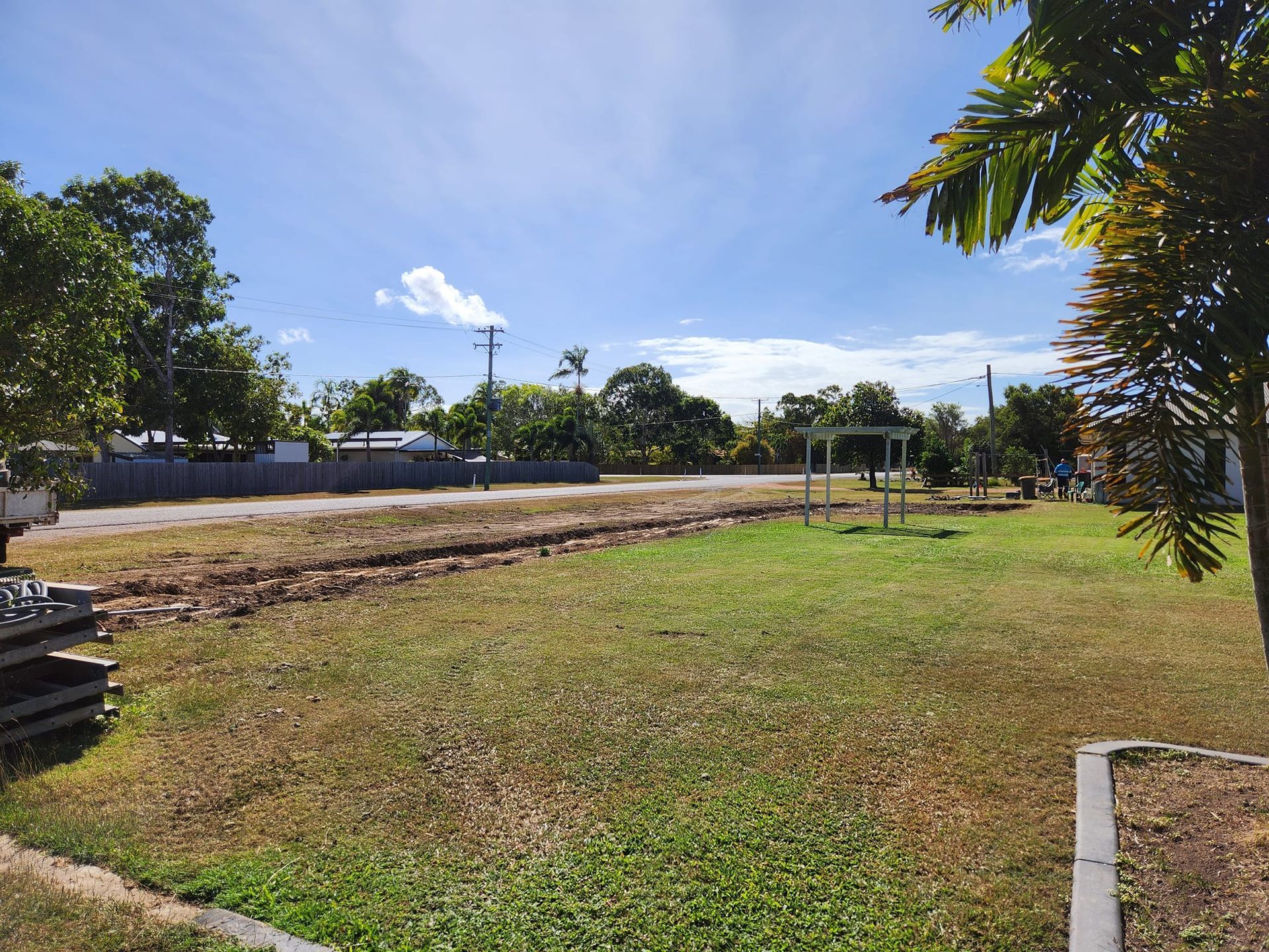 A Grassy Lawn With a Road and Trees Under a Blue Sky — AGM HIRE NQ in Condon, QLD