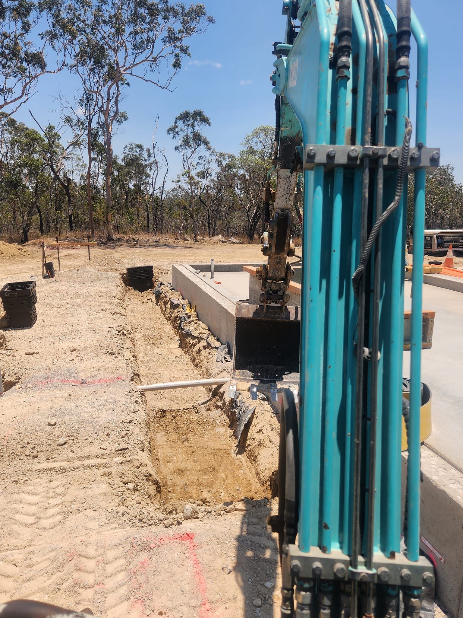 Excavator Digging Trench Beside Concrete Foundation — AGM HIRE NQ in Kelso, QLD