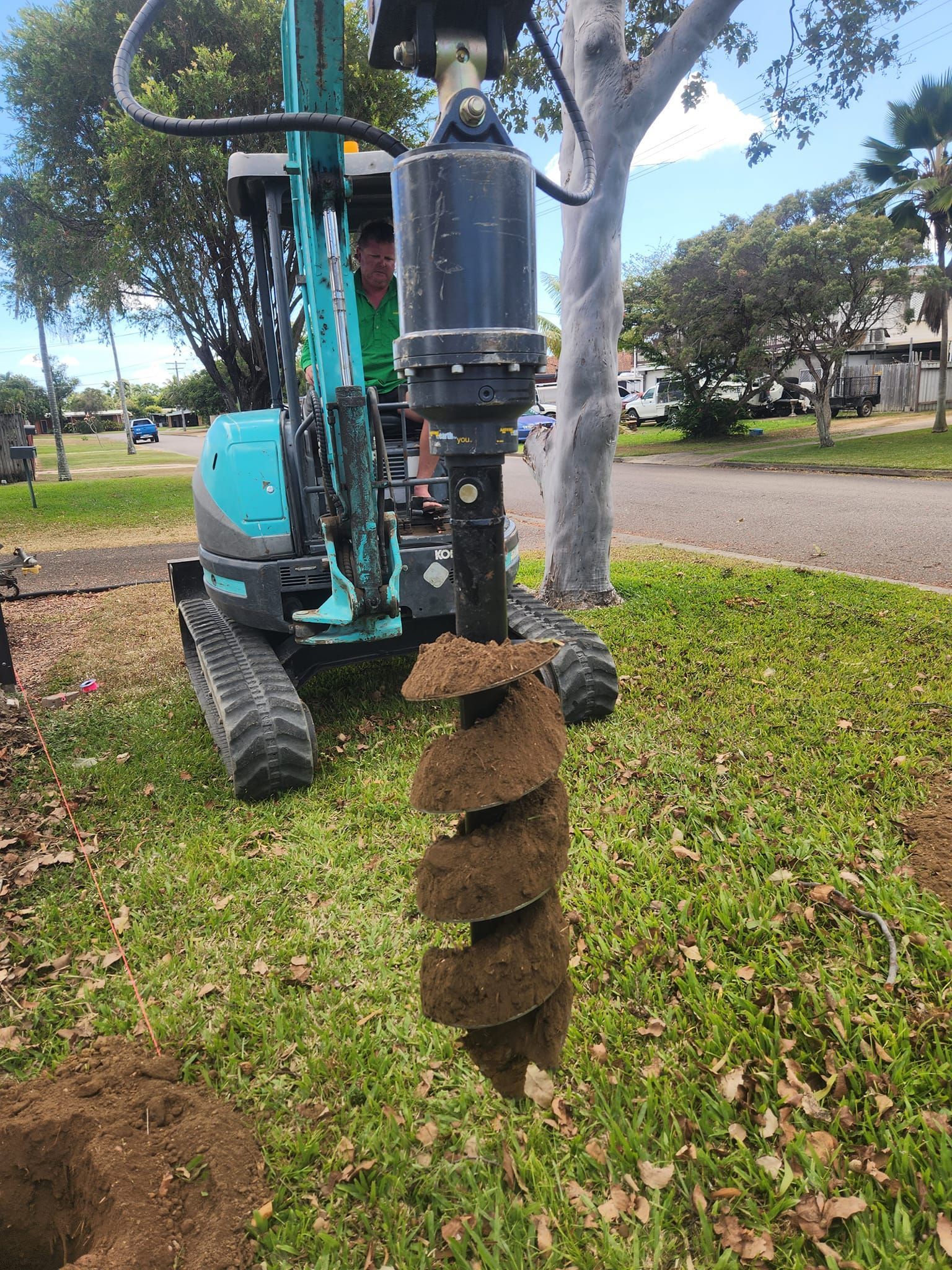 A Person Operates a Teal Excavator — AGM HIRE NQ in Condon, QLD 