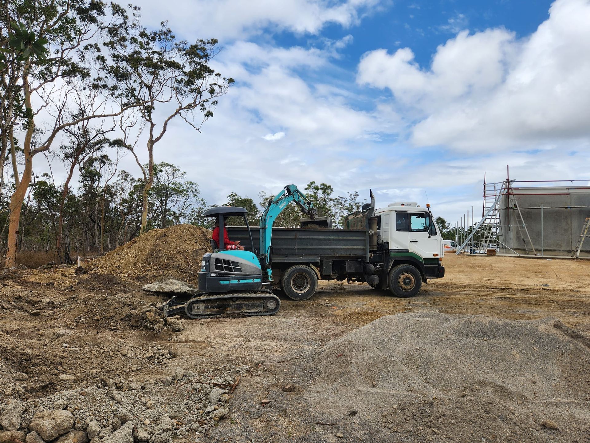 Excavator Loading Dirt Into a Dump Truck on a Construction Site — AGM HIRE NQ in Condon, QLD
