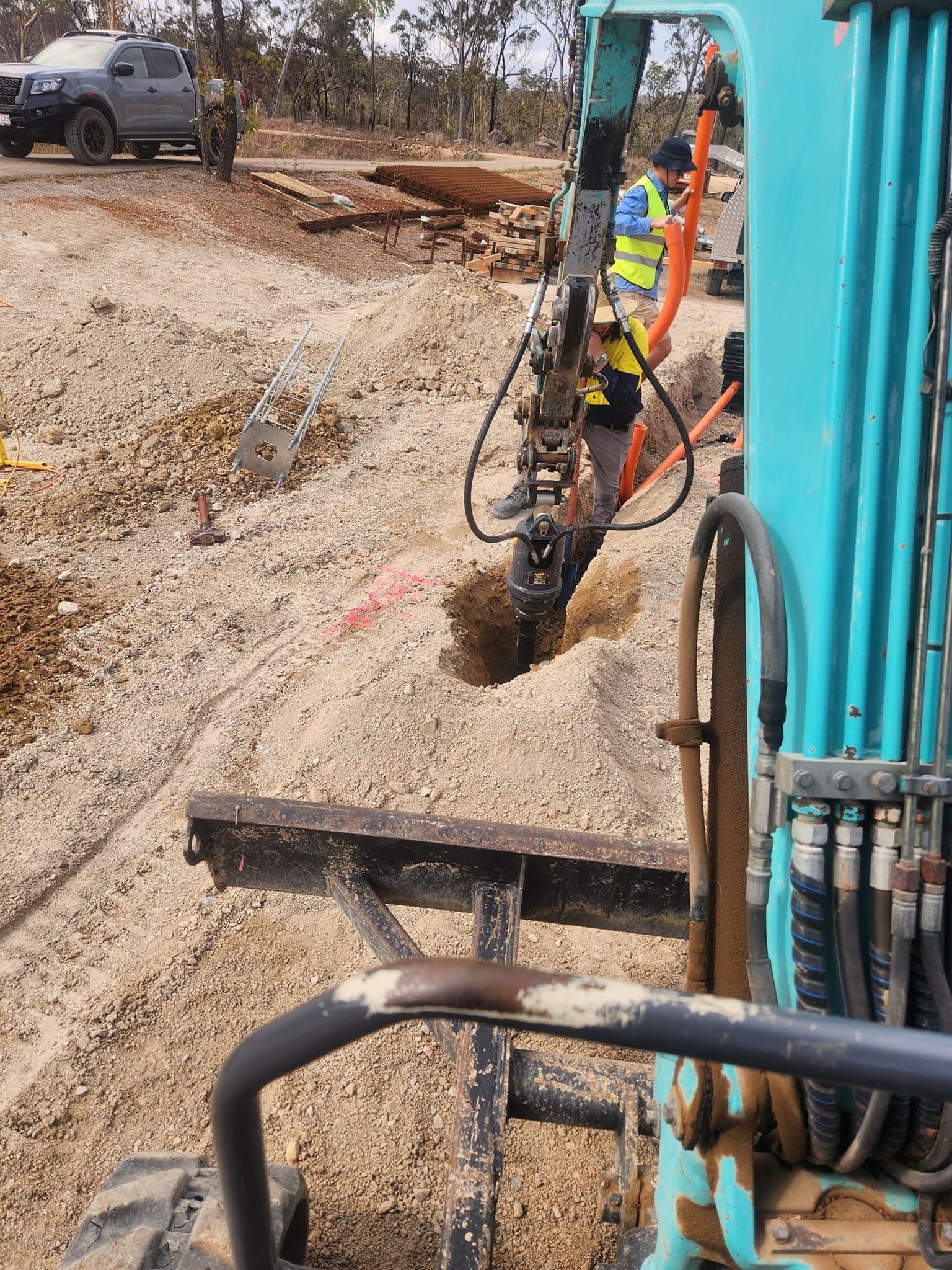 Excavator Drilling Into a Sandy Ground, a Worker in a Vest — AGM HIRE NQ in Condon, QLD