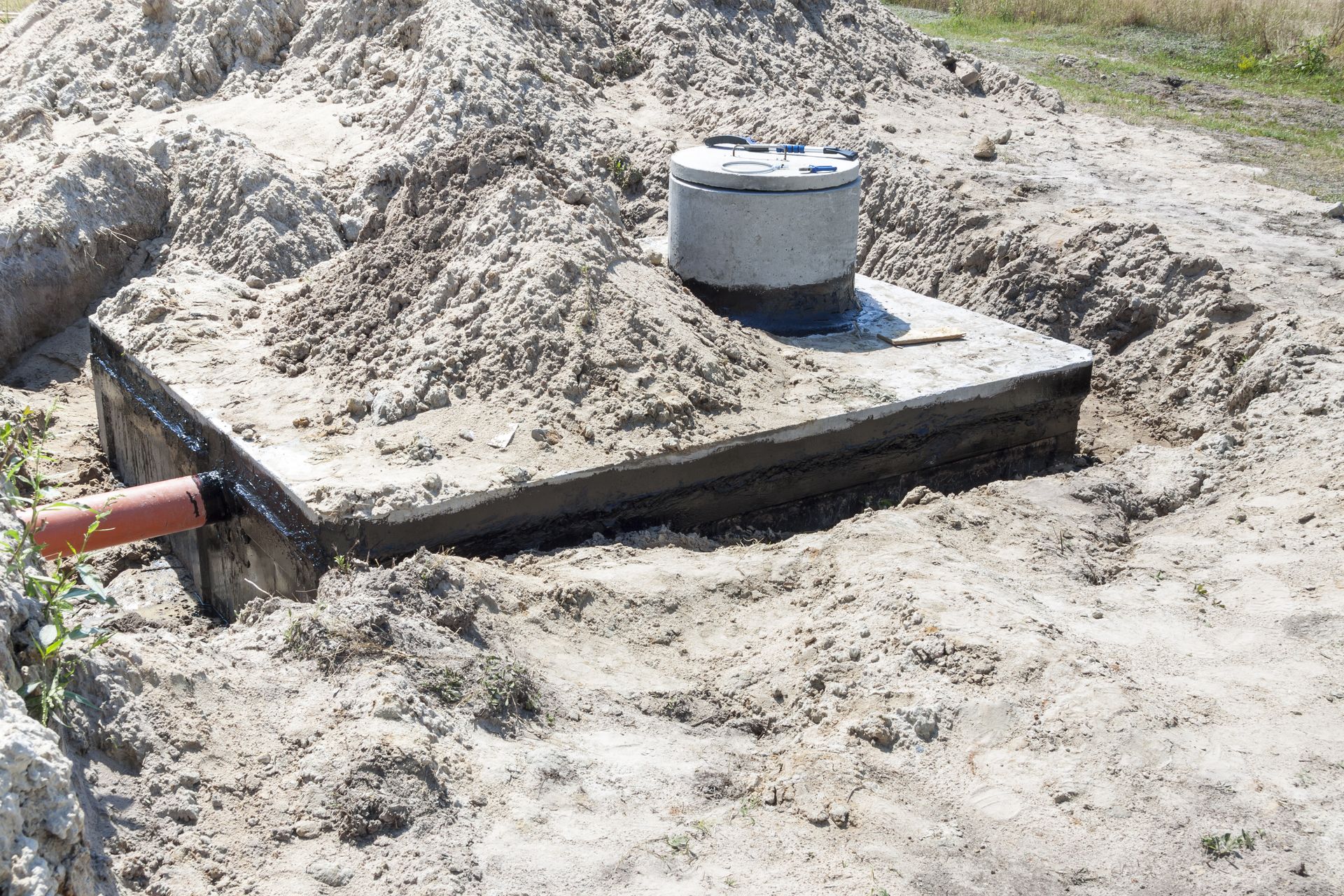 Concrete Septic Tank in a Sand Pit, With a Lid and Orange Pipe Visible — AGM HIRE NQ in Condon, QLD