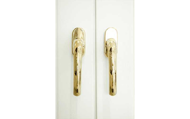 Un primo piano di due maniglie dorate su una porta bianca.