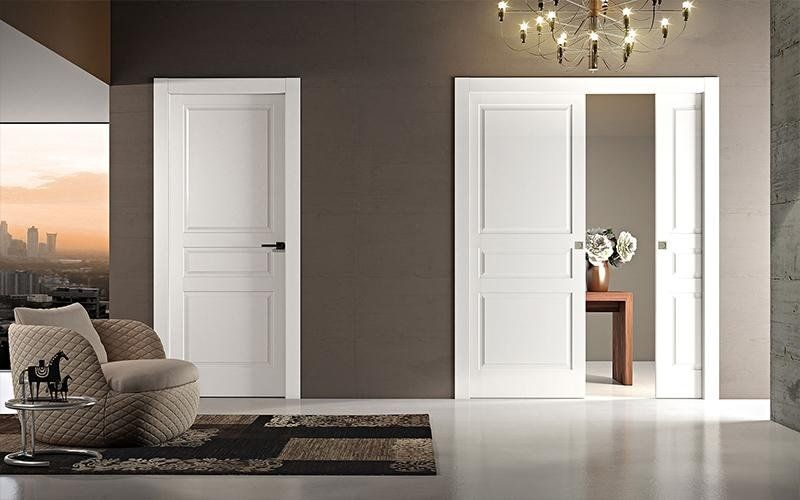 Un soggiorno con due porte bianche, una sedia e un lampadario.