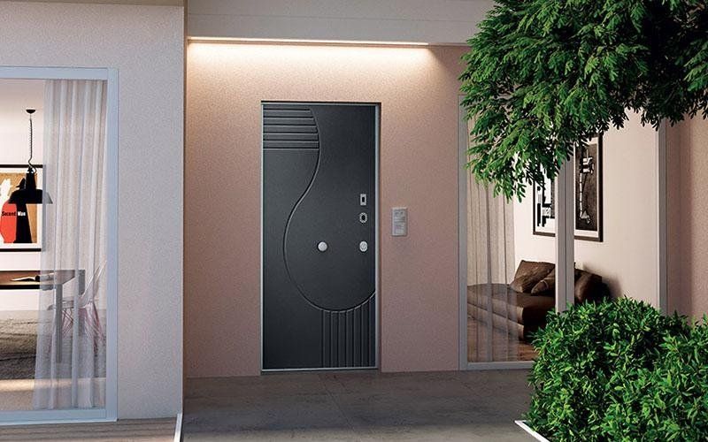 Una porta nera è appoggiata sul lato di un edificio, accanto a una pianta