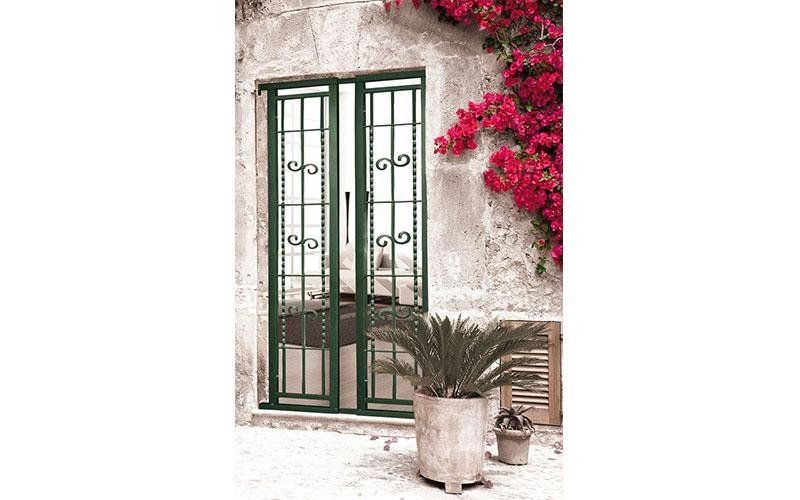 Una finestra con una grata in ferro battuto e una pianta in vaso davanti.