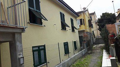 Un edificio giallo con le persiane verdi e una recinzione davanti.