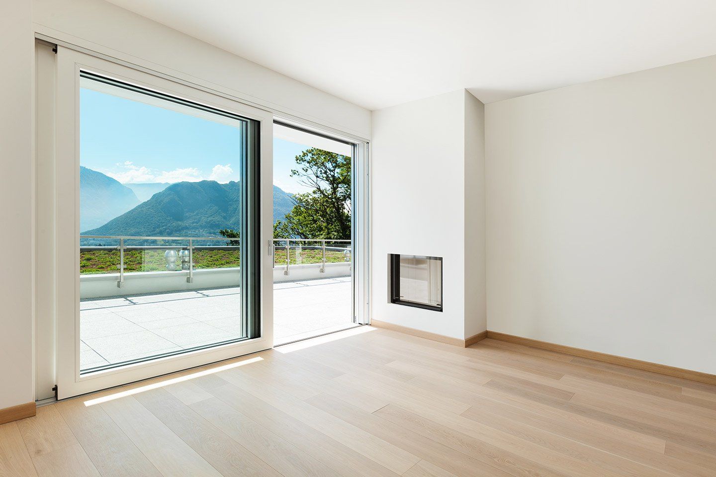 Un soggiorno vuoto con una porta scorrevole in vetro e un camino.