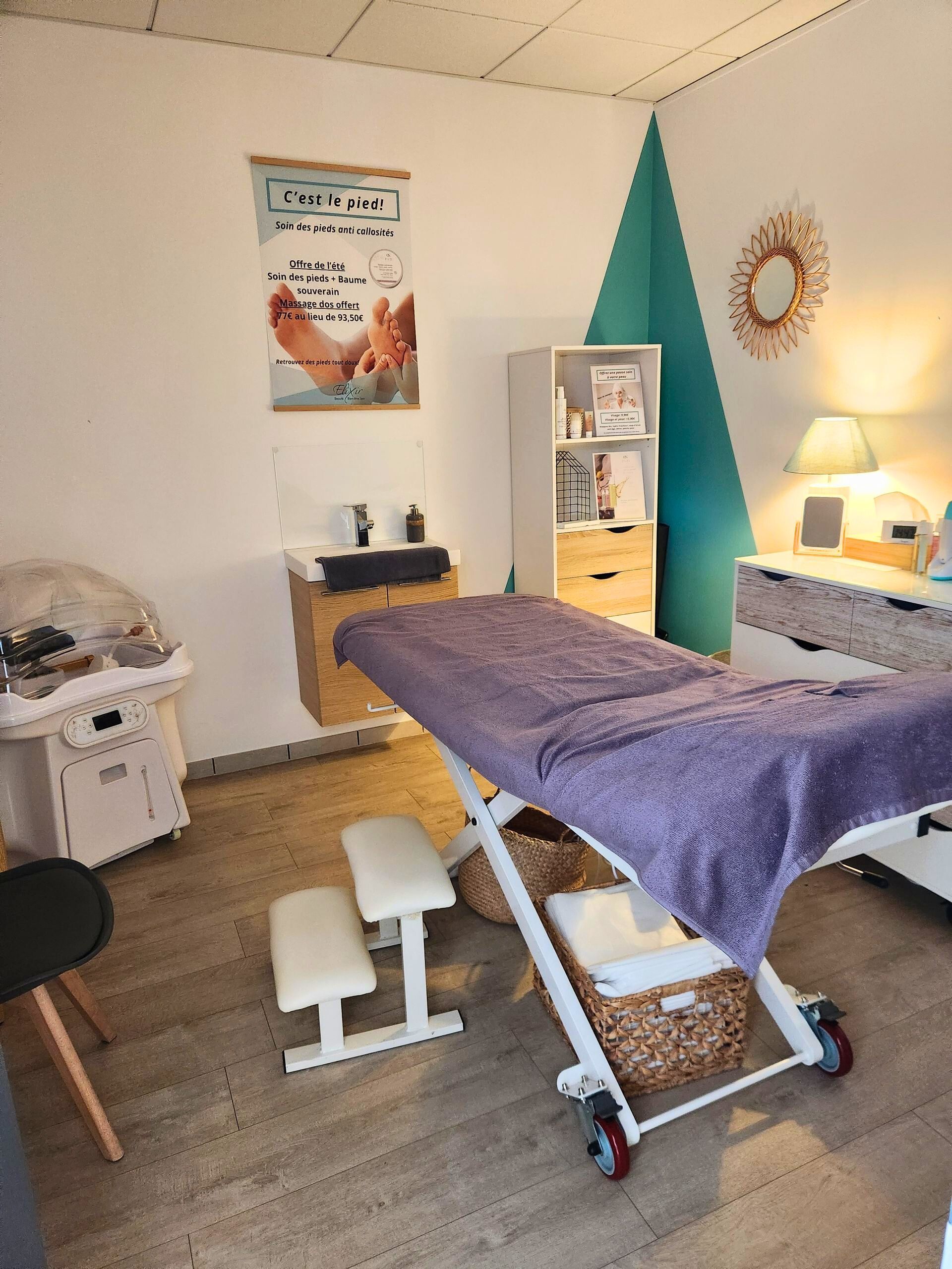 Salle de massage avec table, équipement et décoration ; murs blancs, parquet, touches de turquoise.