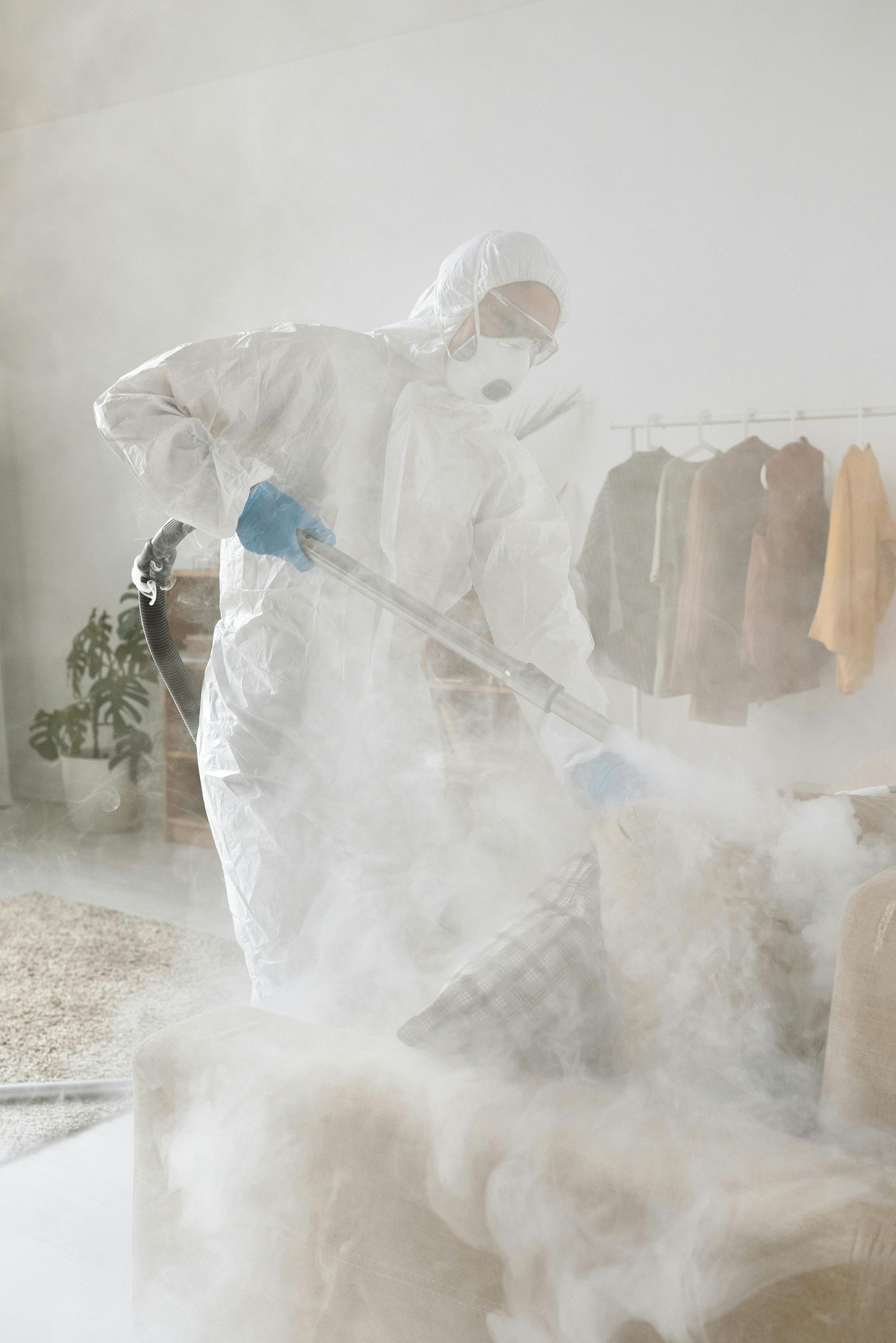 Professional exterminator in protective gear applying pest control treatment