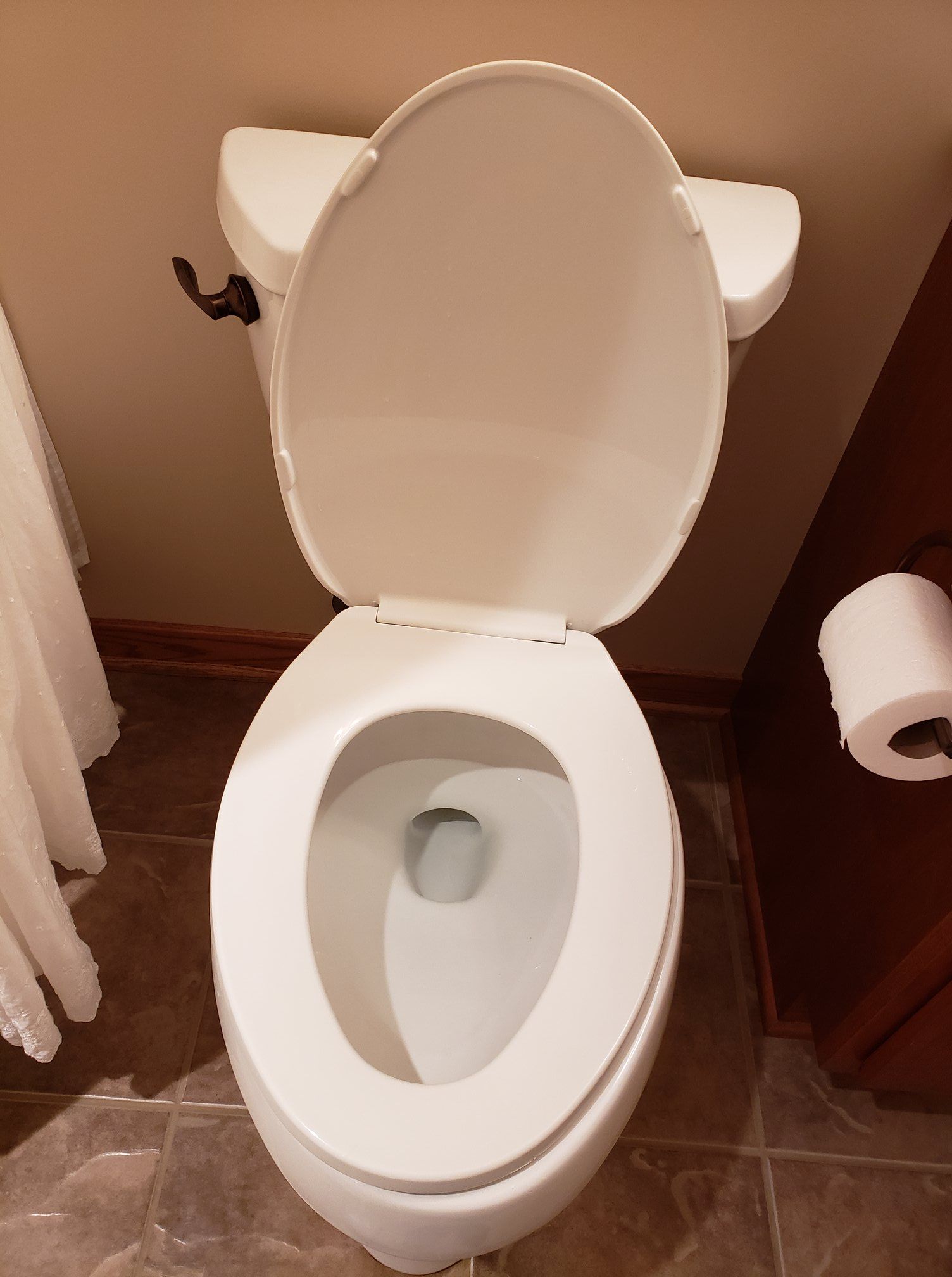 White toilet with open seat in a bathroom.