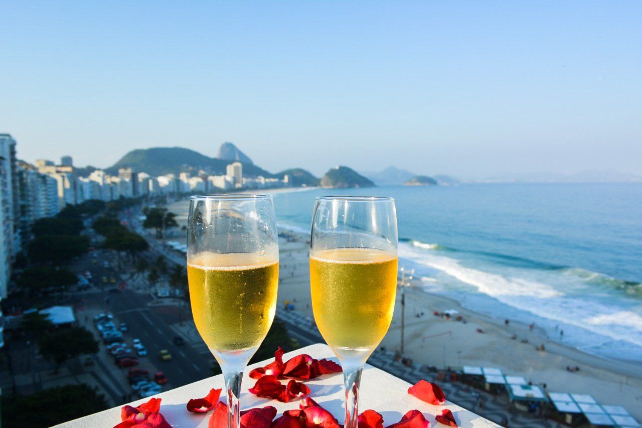 Duas taças de champanhe estão sobre uma mesa com vista para o oceano.