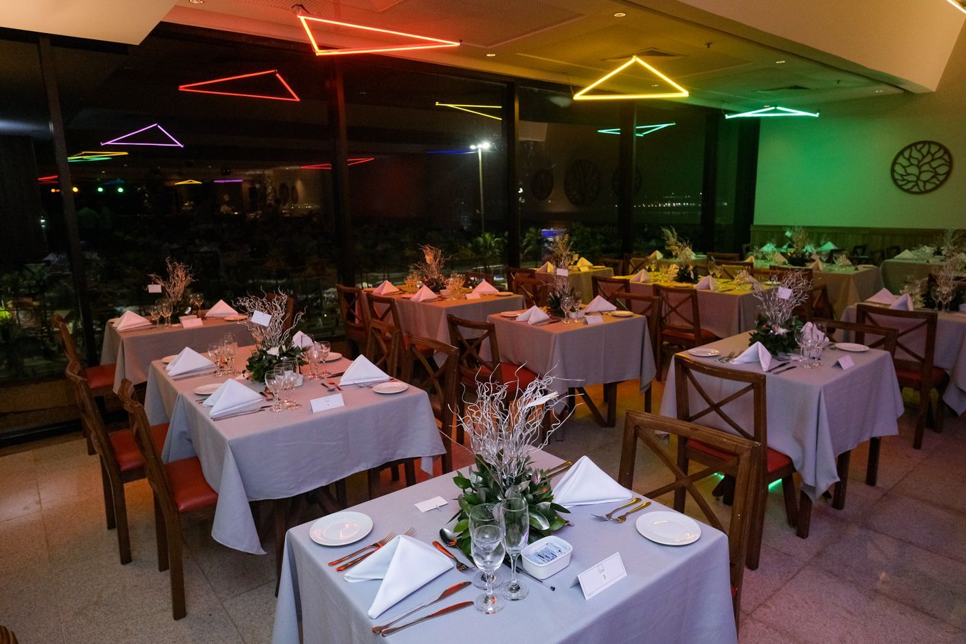 Uma sala de jantar com mesas e cadeiras preparadas para uma festa