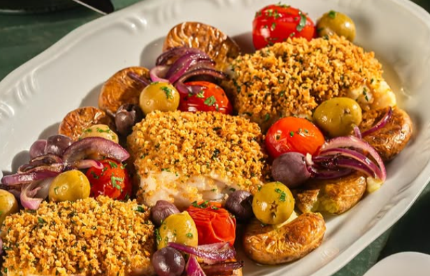An overhead view of a table setting featuring a roasted dish, a baked casserole, glassware, and plates on a green surface.