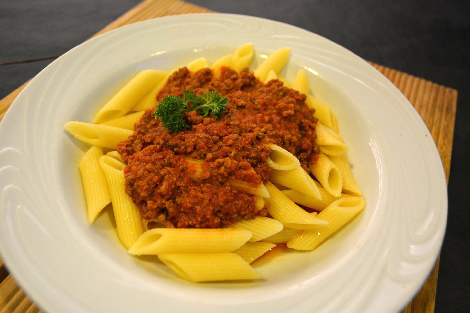 Um prato branco coberto com macarrão e molho de carne