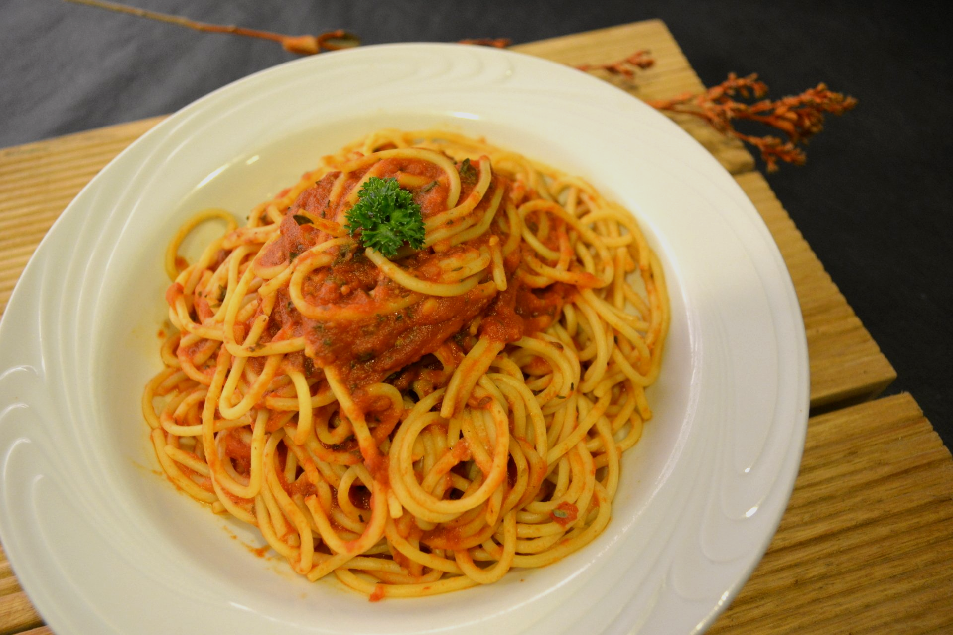 Um prato branco coberto com espaguete e molho sobre uma mesa de madeira.