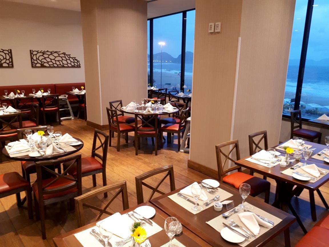 Um restaurante com mesas e cadeiras e uma grande janela