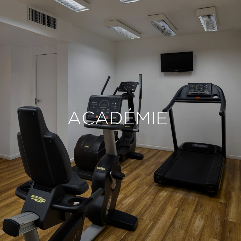 Academia com equipamentos de ginástica: bicicleta ergométrica, elíptico, esteira e TV fixada na parede.